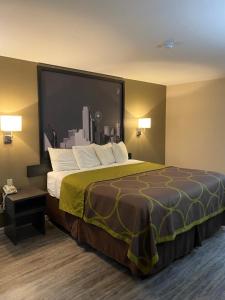 ein großes Bett in einem Hotelzimmer mit einem großen Fenster in der Unterkunft Super 8 by Wyndham Terrell in Terrell
