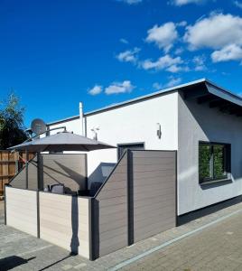 a white house with a fence and an umbrella at Fewo Ostseenähe in Bentwisch