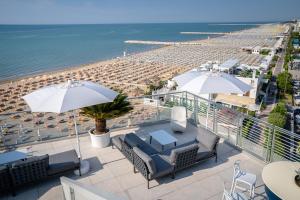 a balcony with chairs and umbrellas and a beach at Hotel Marco Polo in Caorle