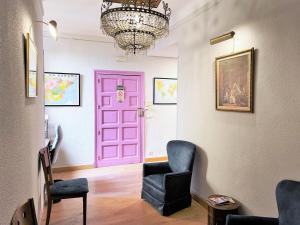 a pink door in a room with a chair and a chandelier at Hostal San Martin in Madrid