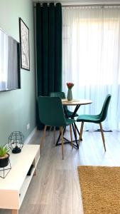 ein Wohnzimmer mit einem Tisch und grünen Stühlen in der Unterkunft Grochowska Apartment in Warschau