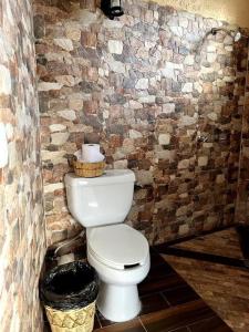 a bathroom with a toilet and a brick wall at Casa Taller zapoteca Huella Carmín in Teotitlán del Valle