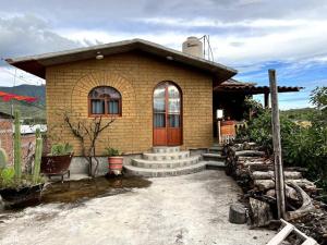 una pequeña casa de ladrillo con escaleras y una puerta en Casa Taller zapoteca Huella Carmín en Teotitlán del Valle