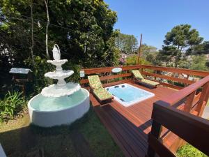 a pool on a deck with a fountain and chairs at Pousada Chateau Colinas in Campos do Jordão