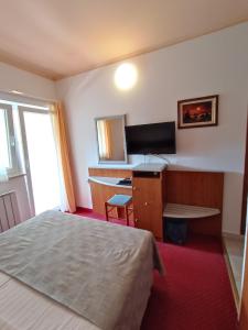 a hotel room with a bed and a desk and a television at Hotel Holiday in Poreč