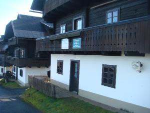 a building with a white building with a wooden roof at Schiappartement Nassfeld in Sonnenalpe Nassfeld