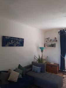 a living room with a blue couch and a plant at Le Peu'ty Cottage in Fougères-sur-Bièvre