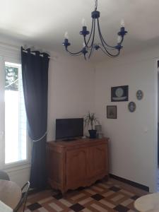sala de estar con TV y lámpara de araña en Le Peu'ty Cottage, en Fougères-sur-Bièvre