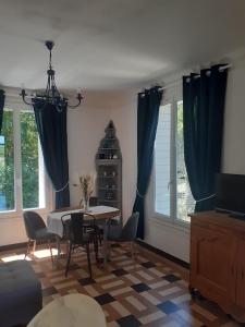 sala de estar con mesa, sillas y ventanas en Le Peu'ty Cottage, en Fougères-sur-Bièvre