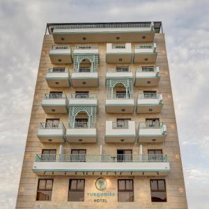 un edificio alto con balcones a un lado. en Turquoise Hotel en Áqaba