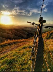 Una bicicleta estacionada en la cima de una colina con la puesta de sol en Apartament pod Szyndzielnią Enduro&Ski, en Bielsko-Biala