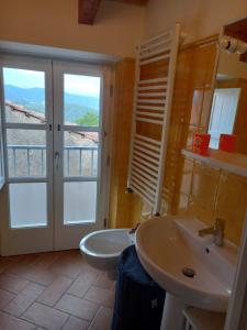 ein Bad mit einem Waschbecken, einer Badewanne und einem Fenster in der Unterkunft Casa Natale in Corvara