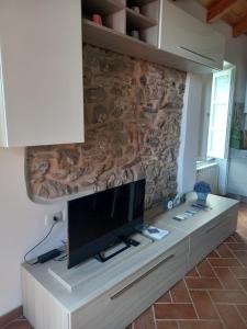 a living room with a tv on a stone wall at Casa Natale in Corvara