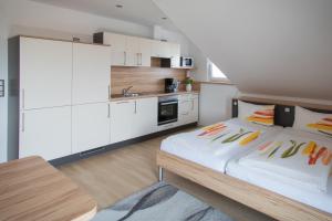 a bedroom with a bed and a kitchen with white cabinets at Gästehaus Sonner in Dietmannsried