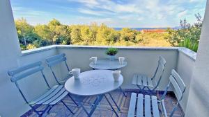 2 tafels en stoelen op een balkon met uitzicht bij Pakostane - VRGADA -appartement 50 m2 avec piscine in Pakoštane