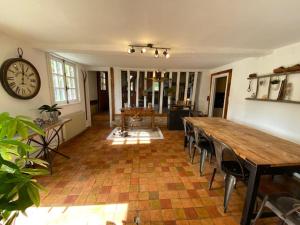 a dining room with a table and a clock on the wall at Gite des Trévignes in Cambremer