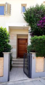 ein Haus mit einer Holztür und einigen Büschen in der Unterkunft Villa Larnaca Bay Resort in Oroklini