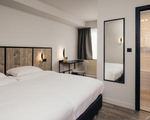 een hotelkamer met een bed, een bureau en een spiegel bij Hotel Au lit des ours in Han-sur-Lesse