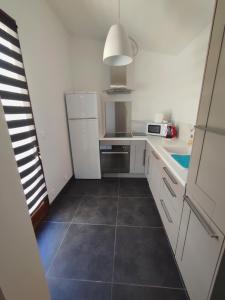 a kitchen with white cabinets and a tile floor at Studio R Homps in Homps