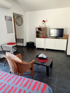 sala de estar con TV, mesa y sillas en Studio R Homps en Homps