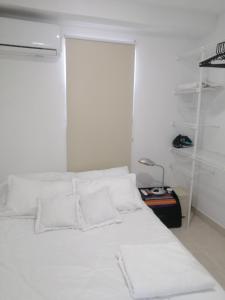 ein weißes Bett mit weißen Kissen in einem Zimmer in der Unterkunft Hermoso Apartaestudio, privado, acogedor, super aseado, excelente ubicación! in Cartagena de Indias