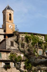 un edificio con una torre dell'orologio sopra di Mas Thomasine Séjour Romantique au calme a Peillon