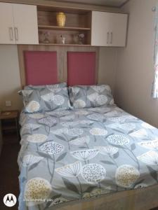 een bed met een blauw en wit dekbed en kussens bij Deluxe 3 Bedroom Caravan with extra en-suite North Shore in Skegness