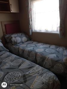 2 camas individuales en un dormitorio con ventana en Deluxe 3 Bedroom Caravan with extra en-suite North Shore, en Skegness
