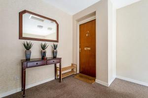 a hallway with a mirror and a wooden door at Penthouse Seafront Largs in Largs