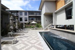 ein Hotel mit einem Pool, Stühlen und Sonnenschirmen in der Unterkunft The Rex Studio Apartment in Knysna