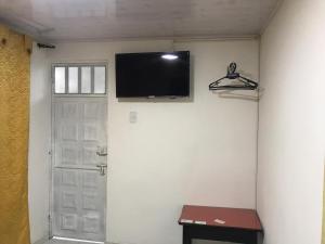 TV de pantalla plana en una pared junto a una puerta en Hotel Casa Nini, en Bogotá