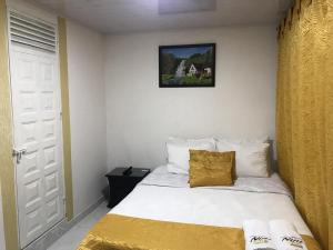 1 dormitorio con cama blanca y cortina amarilla en Hotel Casa Nini, en Bogotá