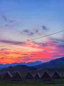 a sunset with a group of houses in a field at Etno selo - Guest House Etno Village - TRSA in Pluzine