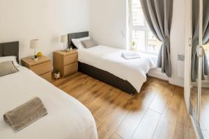 a bedroom with two beds and a wooden floor at Comfortable and Bright Apartment in Tower Bridge in London