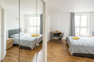 a bedroom with two beds and a mirror at Comfortable and Bright Apartment in Tower Bridge in London