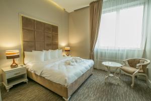 a hotel room with a bed and a chair and a window at Grand Sapphire Hotel in Almaty +91 photos