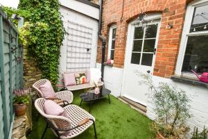 a patio with chairs and a table and a door at Cheerful 3 bed Grade II Central Cottage in Cirencester