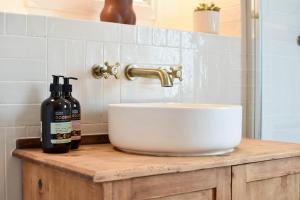 a bathroom sink with two bottles of wine on a counter at Cheerful 3 bed Grade II Central Cottage in Cirencester +17 photos