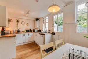 eine Küche mit weißen Schränken sowie einem Tisch und Stühlen in der Unterkunft Cheerful 3 bed Grade II Central Cottage in Cirencester