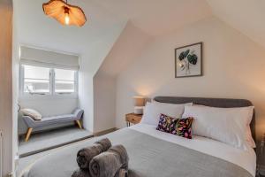 a bedroom with a large bed and a chair at Cheerful 3 bed Grade II Central Cottage in Cirencester