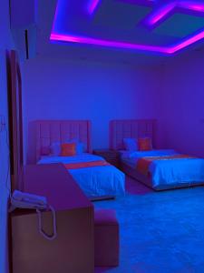 two beds in a room with purple lights at شقق الروشن الجوفي in Al Fayşalīyah