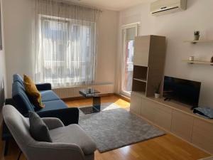 een woonkamer met een blauwe bank en een televisie bij Apartment Jelena in Zagreb