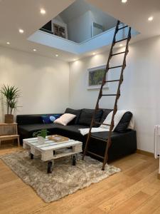 a living room with a black couch and a ladder at Lovely studio at Île Saint-Louis in Paris