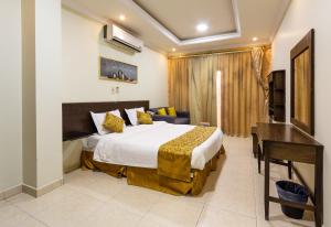 um quarto com uma cama, uma secretária e uma televisão em النايفة للشقق المفروشة em Al Khobar