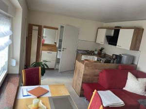 uma sala de estar com um sofá vermelho e uma cozinha em Ferienwohnung Arthur em Luckenwalde