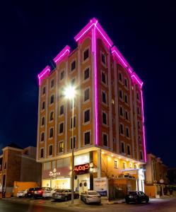 um edifício com luzes cor-de-rosa na lateral em النايفة للشقق المفروشة em Al Khobar