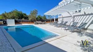 a swimming pool with chairs and a white pergola at Pakostane - VRGADA -appartement 50 m2 avec piscine in Pakoštane