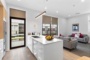 a kitchen and living room with white cabinets and a couch at Academy Apartments in Masterton