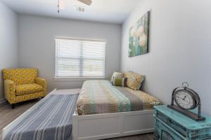 een slaapkamer met een bed, een stoel en een raam bij Nest - a cheerful 4 bedroom, 4.5 bath new townhome in Aggieland in College Station