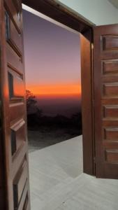 eine offene Tür mit Blick auf den Sonnenuntergang in der Unterkunft Shambala centro de São Tomé das letras in São Thomé das Letras